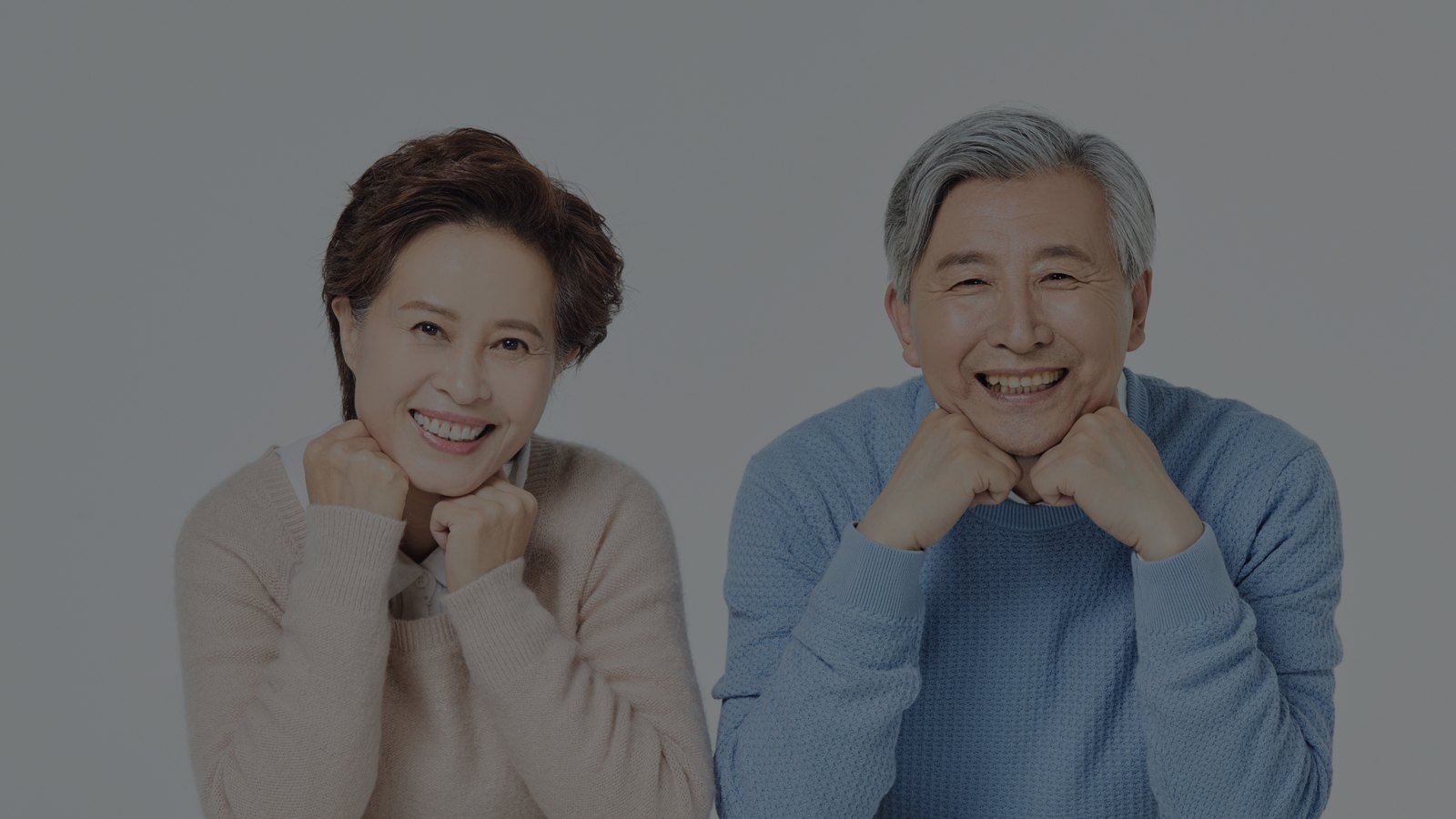 나란히 앉아 웃고 있는 노년 부부